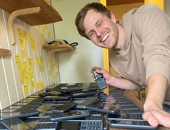 Arne founder of dubpohne posing with a pile of dumbphones
